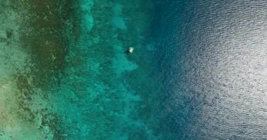 Tropikal deniz yüzeyindeki bir teknenin insansız hava aracı görüntüsüyle sakin mavi deniz. Siquijor, Filipinler.