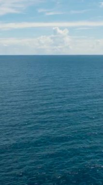 Dalgalar ve bulutlar ve deniz manzarasıyla derin mavi denizin üzerinde uçuyor. Siquijor, Filipinler.