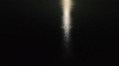 Suyun yüzeyinde ay izi var. Gece deniz manzarası.
