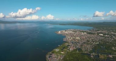 Binaları ve evleri olan Surigao şehrinin havadan görünüşü. Mavi deniz körfezi, açık gökyüzü ve bulutlar. Mindanao, Filipinler.