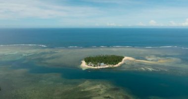 Kıyı şeridinde beyaz kum bulunan tropik bir ada. Turkuaz sularda dalgalı mercan resifleri. Mindanao, Filipinler. Yaz ve seyahat konsepti.