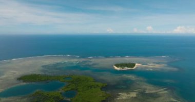 Turkuaz su, beyaz kumlu plajlı tropikal küçük bir adada sarılı. Mercan resifleri ve dalgalar. Mindanao, Filipinler.