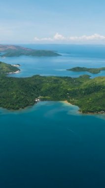 Yağmur ormanları olan tropikal adaların çarpıcı manzarası. Mavi deniz yüzeyi, mavi gökyüzü ve bulutlar. Deniz Burnu. Mindanao, Filipinler. Dikey görünüm.