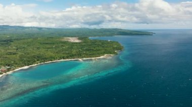 Etrafı güzel dalgalarla çevrili uzun beyaz kumlu bir sahili olan mavi okyanusta bir kara parçası. Siquijor, Filipinler.