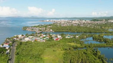 Kuleleri ve evleri olan sahil şehri. Balık çiftliğinin tarım arazisi. Mindanao, Filipinler.
