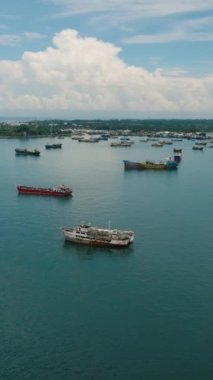 Groups of Fishing Boats floating and cargo ship over the sea in Zamboanga. Mindanao, Philippines. Seascape. Aerial drone view. Vertical video.