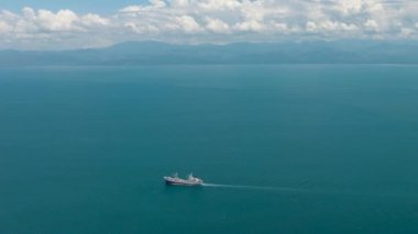 Mavi okyanusun mavi gökyüzü bulutlu ve gemisinin drone görüntüsü. Mavi su ve gökyüzü manzarası. Mindanao, Filipinler. Seyahat kavramı.