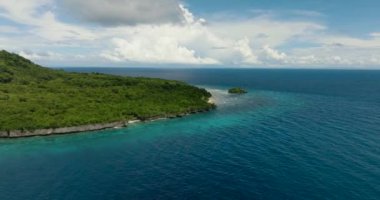 Tamamen suyla çevrili beyaz sahil kıyısında küçük bir adayla güzel tropik adanın üzerinde uçuyor. Siquijor, Filipinler.