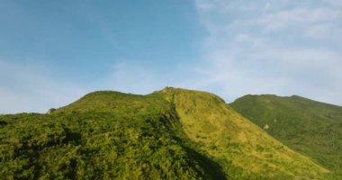 Dağ manzaralı yeşil tepe ve mavi gökyüzü ve bulutların altındaki uçurum. Camiguin Adası. Filipinler.