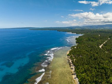 Kumlu sahil şeridinde dalgaları olan güzel mavi deniz. Mavi gökyüzü ve bulutlar. Mindanao, Filipinler. Deniz Burnu. Hava görünümü.