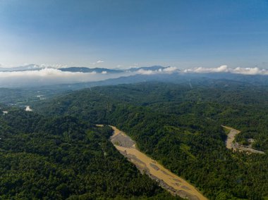 Nehrin tropikal dağın üzerindeki havadan görünüşü. Mavi gökyüzü ve bulutların altındaki yeşil orman. Mindanao, Filipinler.