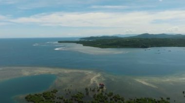 Tropikal ada ve mavi denizin havadan görünüşü. Mavi gökyüzü ve bulutlar. Mindanao, Filipinler.