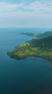 Yağmur ormanları ve mavi denizli tematik bir manzara. Mavi gökyüzü ve bulutlar. Mindanao, Filipinler. Dikey görünüm.