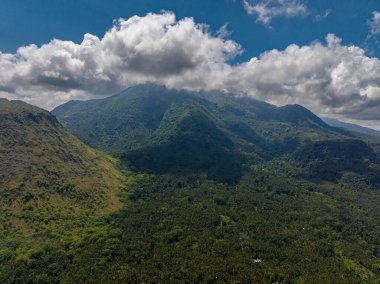 Yeşil tepeli, yağmur ormanlı ve ormanlı bir dağ manzarası. Mavi gökyüzü ve bulutlar. Camiguin Adası. Filipinler.