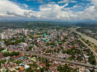 Cagayan de Oro City 'de bir yerleşim alanı, nehir kenarındaki binalar. Mavi gökyüzü ve bulutlar. Mindanao, Filipinler.
