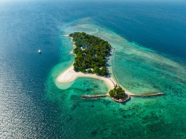 Güneş ışığı yansımalı mavi okyanus ve yukarıdan manzaralı beyaz sahil beldesi. Buenavista Adası. Samal, Davao. Filipinler.
