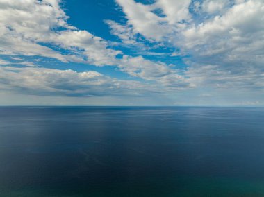 Mavi gökyüzü ve bulutlarla mavi denizin üzerinde uçuyor. Camiguin, Filipinler.