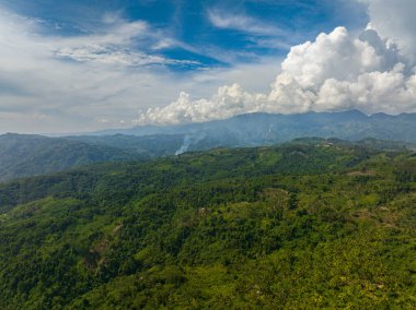 Bereketli bitki örtüsü ve yemyeşil ormanı olan tropik bir dağ. Mavi gökyüzü ve bulutlar. Mindanao, Filipinler.