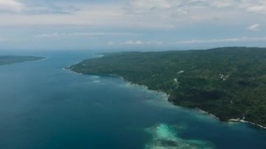 Yeşil dağ, mavi deniz, gökyüzü ve bulutları olan tropikal adanın en üst manzarası. Samal Adası. Davao, Filipinler.