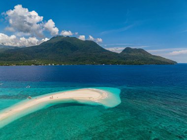 Transsaparent deniz suyu, beyaz kumsalda dalgalar ve Camiguin Adası 'nda tekneler. Mavi gökyüzü ve bulutlar. Filipinler.