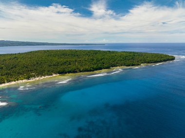 Tropikal adalardaki kıyılarda dalgalı mavi deniz. Mavi gökyüzü ve bulutlar. Mindanao, Filipinler. Deniz Burnu.
