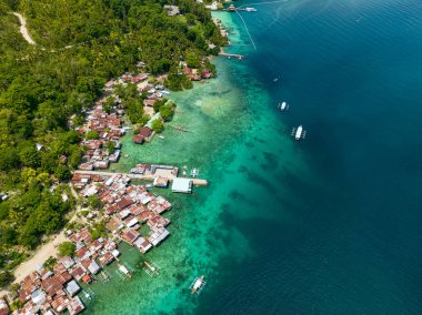 Kıyı şeridindeki turkuaz suyun üzerindeki evler. Mavi deniz ve dalgalar. Samal Adası. Davao, Filipinler.