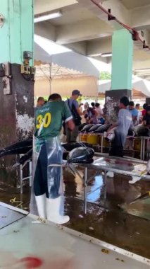 Ton balığının kuyruğunu ve yüzgeçlerini çıkaran adam. General Santos 'taki Tuna Limanı. Filipinler. Dikey görünüm.