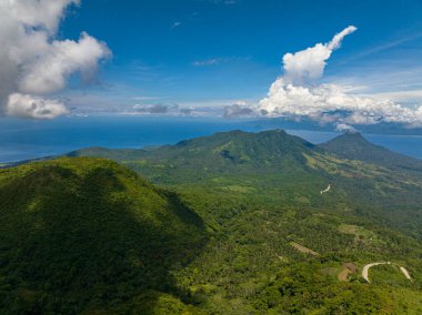 Camiguin Adası 'nda yeşil ormanı ve ormanı olan bir dağ. Mavi gökyüzü ve bulutlar. Filipinler. Yukarıdan görüntüle.