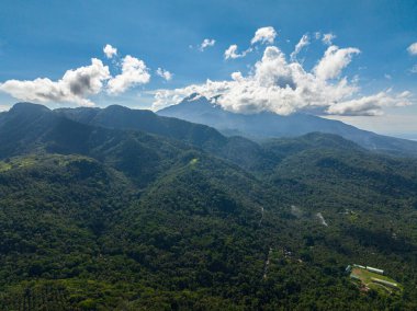 Mavi gökyüzü ve dağ ormanlarının üzerindeki bulutlar ve yeşil vadi. Camiguin Adası. Filipinler.