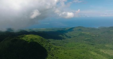 Bulutlar dağı yeşil ağaçlar ve ormanla kapladı. Mavi gökyüzü ve bulutlar. Camiguin Adası. Filipinler.