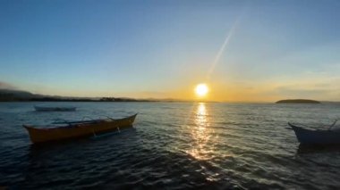 Deniz yüzeyinde gün batımı, deniz suyunda yüzen tekneler. Filipinler.