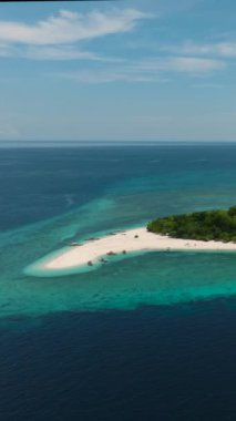 Mantigue Adası beyaz sahil ve turkuaz suyla çevrili. Mavi deniz, mavi gökyüzü ve bulutlar. Camiguin, Filipinler. Dikey video.