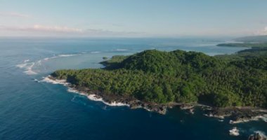 Tropikal adadaki kayalık kıyılarda okyanus dalgaları. Mavi gökyüzü ve bulutlar. Surigao del Sur, Filipinler.