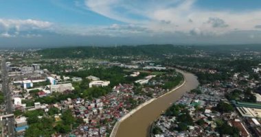 Şehir merkezinde, nehir kenarındaki binalar ve evler. Mavi gökyüzü ve bulutlar. Davao Şehri. Mindanao, Filipinler.