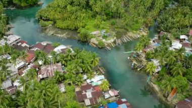 Tropikal orman ve balıkçı evleriyle çevrili Bogac Soğuk Baharı manzarası. Surigao del Sur. Filipinler.