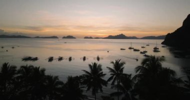 Corong Corong Sahili 'nde alacakaranlıkta panorama manzarası, palmiye ağaçları ve deniz üzerinde tekneler. El Nido, Palawan. Filipinler.