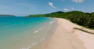 Nacpan Sahili 'nde kristal berrak turkuaz su ve dalgalar. Mavi gökyüzü ve bulutlar. El Nido, Palawan. Filipinler.