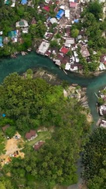 Açık deniz manzarası ve tropikal ormanlarla çevrili geleneksel tekneler. Surigao del Sur 'da Bogac Soğuk Baharı. Filipinler. Dikey görünüm.