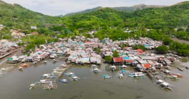 Balıkçı tekneleri ve dikiş evleri. Dağ yamacında yeşil bitkilerle dolu bir kasaba. Koron. Palawan, Filipinler.