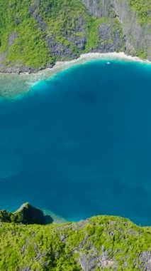Tapiutan Adası ile Matinloc Adası arasında sahili olan güzel Mavi Deniz. El Nido, Palawan. Filipinler. Dikey görünüm.