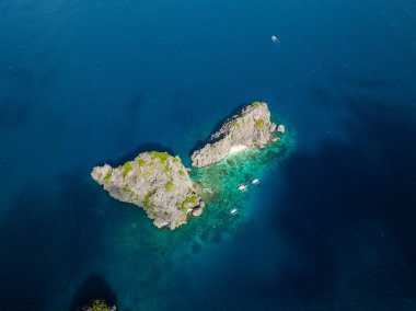Mavi denizde tekneleri olan ikiz kayalar. El Nido, Palawan. Filipinler.