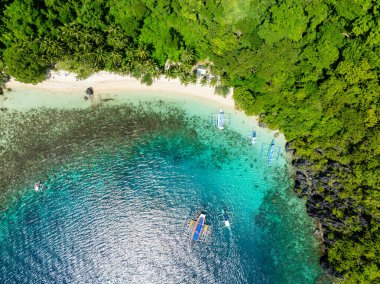 Teknelerin üzerindeki güneş ışığı berrak sularda yansıyor. Pasandigan Koyu. Cadlao, El Nido, Palawan. Filipinler.