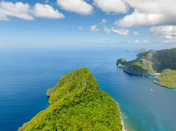 Helikopter Adası üzerindeki yeşillik bitkileri ve ağaçlar. Mavi gökyüzü ve bulutlar. El Nido, Filipinler.