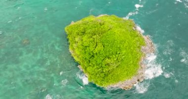Yukarıdan, turkuaz deniz suyu ve dalgalarla çevrili yeşil bitkilerle çevrili bir ada. Boracay, Filipinler.
