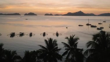 Corong Corong Sahili 'nde alacakaranlıkta panorama manzarası, palmiye ağaçları ve deniz üzerinde tekneler. El Nido, Palawan. Filipinler.