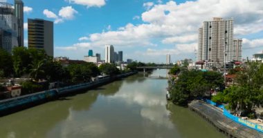 Metro Manila 'daki yerleşim yerlerinin arasındaki nehir. Mavi gökyüzü ve bulutlar. Filipinler.