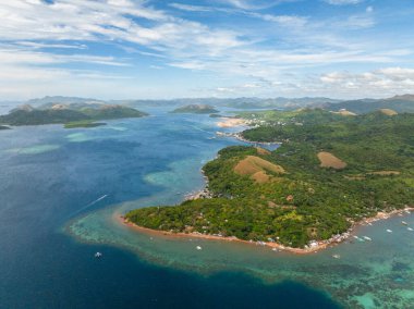 Berrak sularda tekneleri olan tropik bir manzara ve evleri olan bir ada. Coron, Palawan. Filipinler.