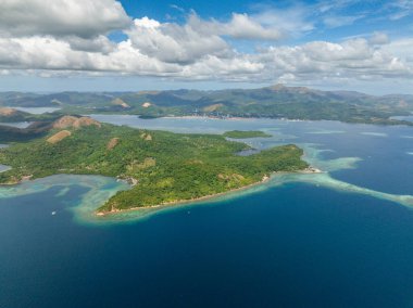 Uson Adası 'nda turkuaz deniz suyu ve mercanlarla dolu bir sahil şeridi. Mavi gökyüzü ve bulutlar. Koron, Filipinler.