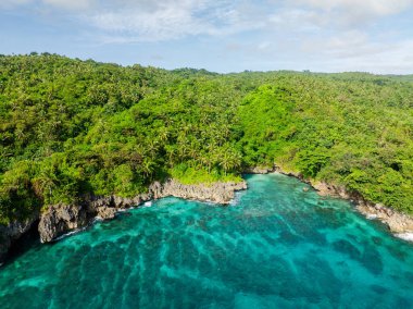 Turkuaz deniz suyu ve kaya dalgalarıyla kıyı şeridi. Carabao Adası. San Jose, Romblon. Filipinler.