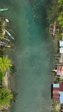Surigao del Sur 'da Tropik Orman ve Bogac Soğuk Baharı. Balıkçıların evleri ve tekneleri suyun üzerinde. Filipinler. Dikey görünüm.
